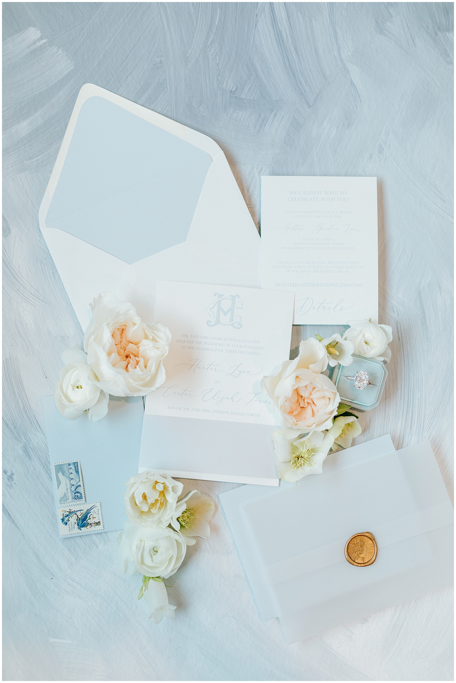 Dusty Blue Invitation Suite Flatlay with Florals, Wax Seal, and vintage stamps