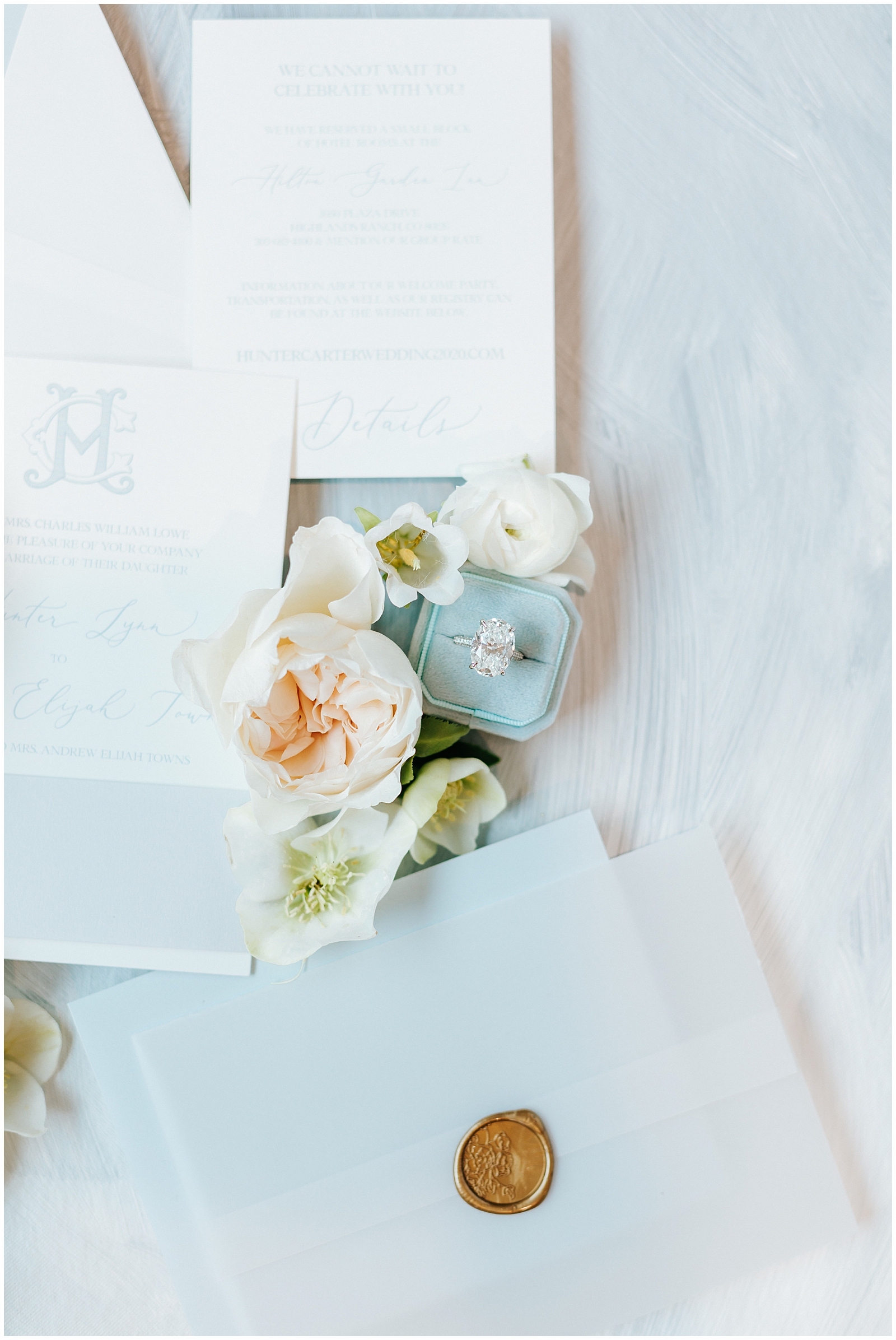 10 carat wedding engagement ring surrounded by florals and wedding invitation suite flatlay