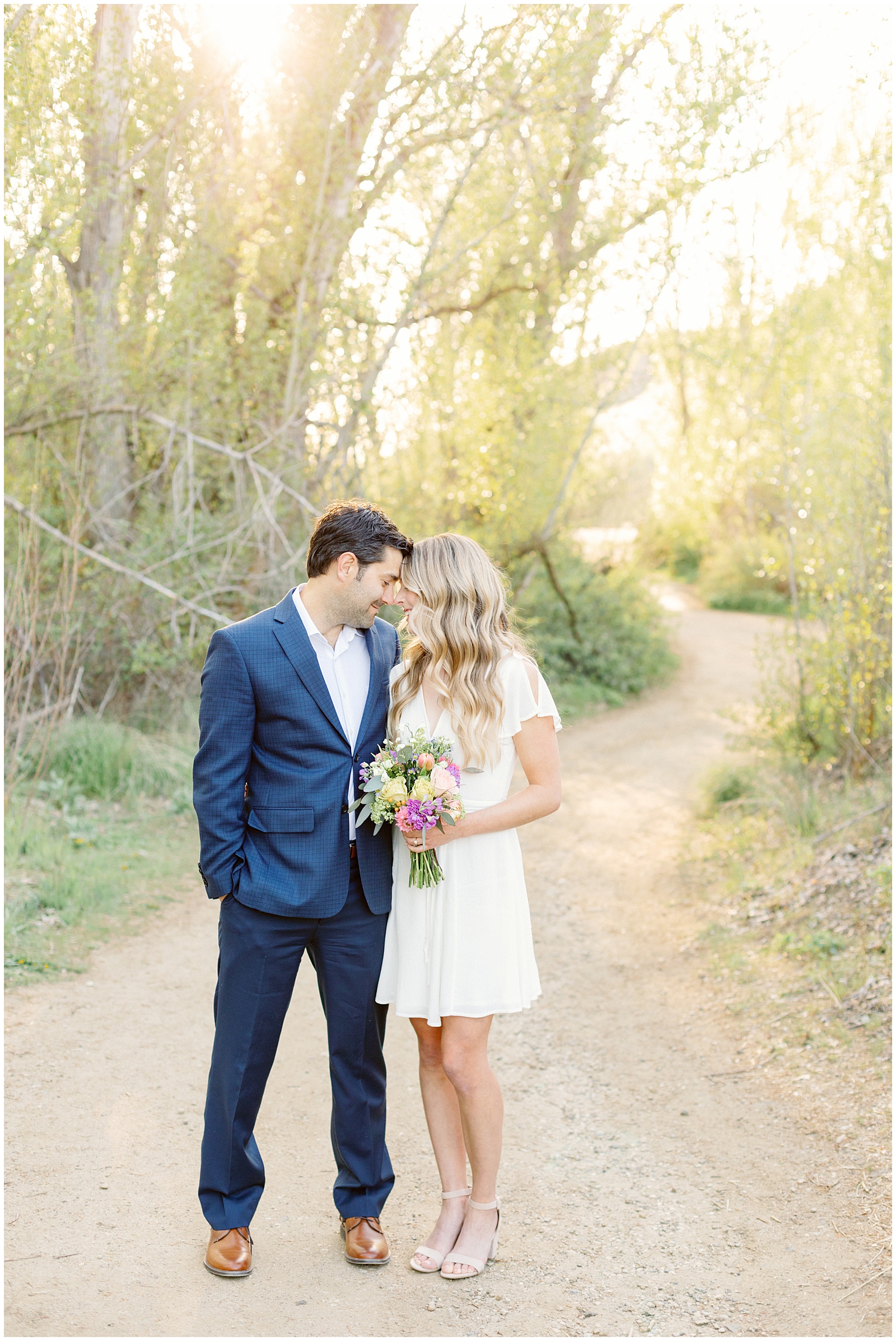 Dreamy Elegant Boise Foothills Engagement Session - Groom in Navy Plaid Suit and Bride in White Dress with Fresh Flowers